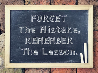 Wall Mural - Motivational and inspirational wording - Forget The Mistake, Remember The Lesson written on a black board.