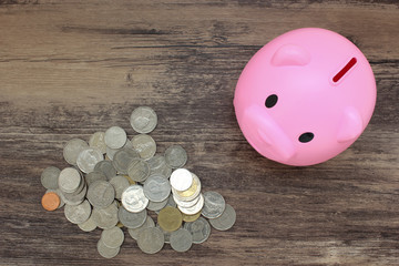 Piggy bank and pile of coins on wood table. Saving and finance concept.