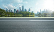 © jamesteohart - Side view of asphalt road highway with lake garden and modern city skyline in background.