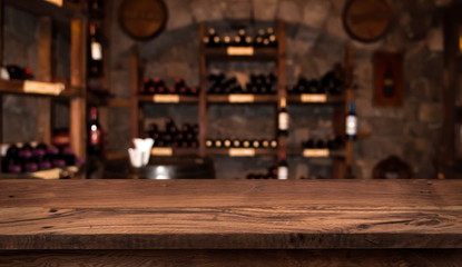 Defocused dark wine cellar background with wooden table in front