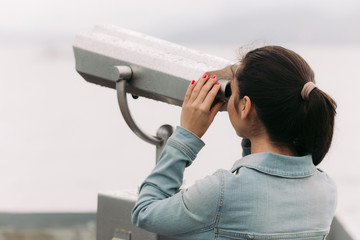 Wall Mural - female tourist looking through coin operated binoculars with sea view