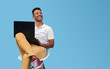 © kegfire - Cheerful black student with laptop looking away