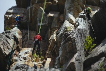 Wall Mural - Group of climbers during the competition against the backdrop of a complex rocky terrain. Tilt-Shift effect.