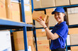 © stnazkul - Portrait of woman delivery staff in blue uniform holding parcel box size D in warehouse