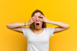 © Asier - Young natural caucasian woman blink through fingers frightened and nervous.
