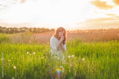 Fotomural Girl closed her eyes, praying in a field during beautiful sunset