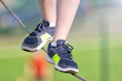 boy walking on tightrope closeup front view of kid feet in sneakers on steel rope against blurred background sport outdoor hiking activity authentic lifestyle concept natural color photo