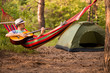 © Svetlana - young caucasian man in hat play guitar and swinging in hammock of weekend morning in camp rest