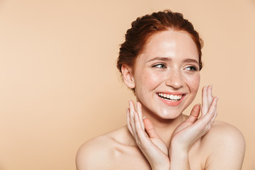 Amazing young redhead woman posing isolated over beige wall background.