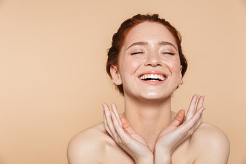 Wall Mural - amazing young redhead woman posing isolated over beige wall background.