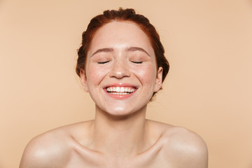 Wall Mural - amazing young redhead woman posing isolated over beige wall background.