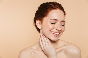 Wall Mural - amazing young redhead woman posing isolated over beige wall background.