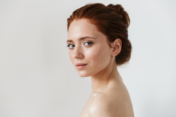 Young redhead woman posing isolated over white wall background.