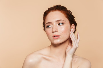Wall Mural - amazing young redhead woman posing isolated over beige wall background.