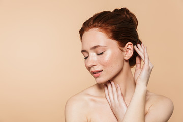 Amazing young redhead woman posing isolated over beige wall background.