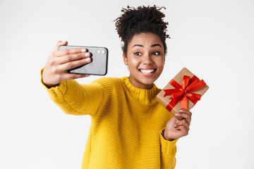 Wall Mural - Image closeup of pretty african american woman looking at smartphone while holding gift box