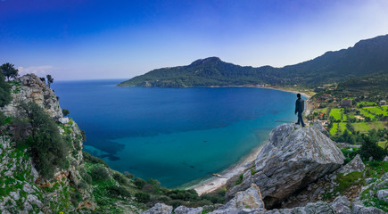 Wall Mural - The man watching the panoramic view of marmaris, on the edge of the cliff. Kumlubuk, Marmaris, Turkey. Amos Ancient city. Amazing coastline. Holiday, travel and tourism concept.