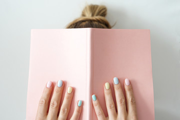 Stylish trendy color female manicure . Women s hands keep pink note pad