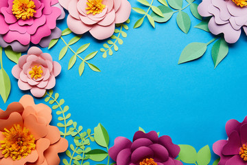 Sticker - top view of multicolored bright paper cut flowers with green leaves on blue background with copy space