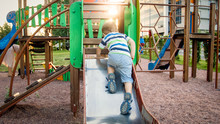 Image Of Happy Smiling Cheerful Toddler Boy Riding And Climbing On The Big Children Playground At Park