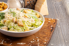 Caesar Salad On A Wooden Table With Grated Parmesan