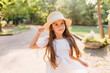© Look! - Joyful little lady with long light-brown hair posing in park in sunny warm day. Outdoor portrait of pretty dark-eyed girl in cute white dress dancing on the street enjoying summer vacation.