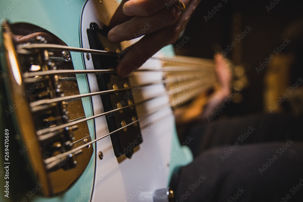 Closeup on the bass guitar strings, while someone is playing - obrazy, fototapety, plakaty 
