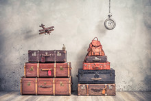 Vintage Outdated Trunks Luggage, Old Antique Valises, Classic Leather Backpack, Flying Wooden Toy Plane And Hanging Big Clock Front Concrete Background. Travel By Air Concept. Retro Style Photo