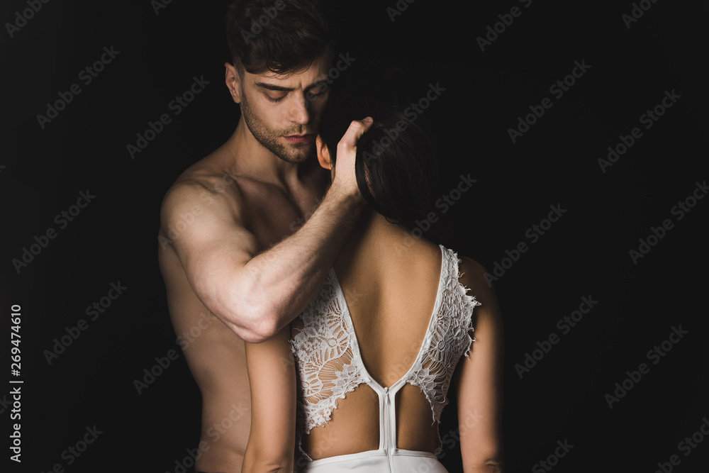 handsome shirtless man hugging sexy girlfriend in white lingerie isolated on black - obrazy, fototapety, plakaty 