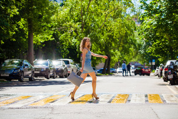 Wall Mural - Young beautiful woman in a blue short dress walking on the road