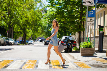 Wall Mural - Young beautiful woman in a blue short dress walking on the road