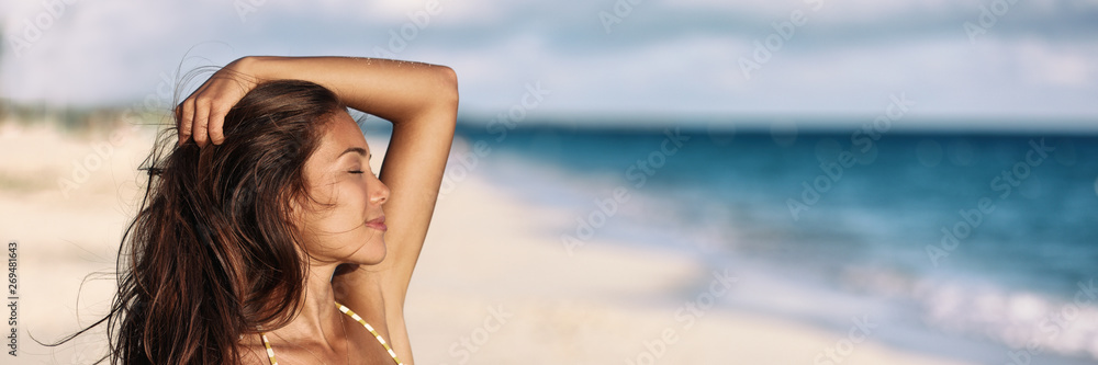 Banner woman relaxing touching her hair wellness summer holiday ocean beach panoramic background on tropical Caribbean summer vacation panorama. Asian girl breathing clean air. - obrazy, fototapety, plakaty 