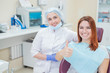© Михаил Решетников - Happy women a dentist and patient after treating teeth at the dental office, smiling and looking towards the camera. Happy patient shows thumb as an endorsement. Dental equipment.