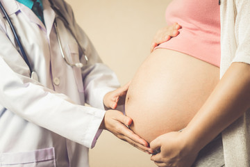 Happy pregnant woman visit gynecologist doctor at hospital or medical clinic for pregnancy consultant. Doctor examine pregnant belly for baby and mother healthcare check up. Gynecology concept.