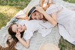 © Look! - Overhead portrait of relaxing girls lying on blanket and smiling after photoshoot. Excited young woman with camera resting on the grass playing with joyful daughter.