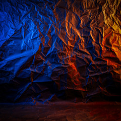 Wall Mural - Texture of crumpled black paper. Close up black background of crumpled cardboard under color blue and orange studio light