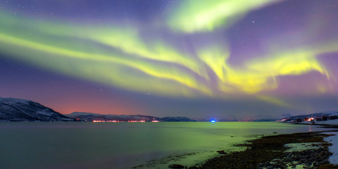 snow storm on the empty road - snow covered road on a winter - northern lights in the sky over troms