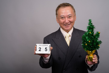 portrait of mature asian businessman against gray background