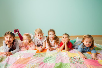 Group of six kids laying on the floor at home