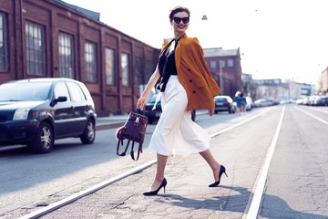 Happy young business woman walking on the street.