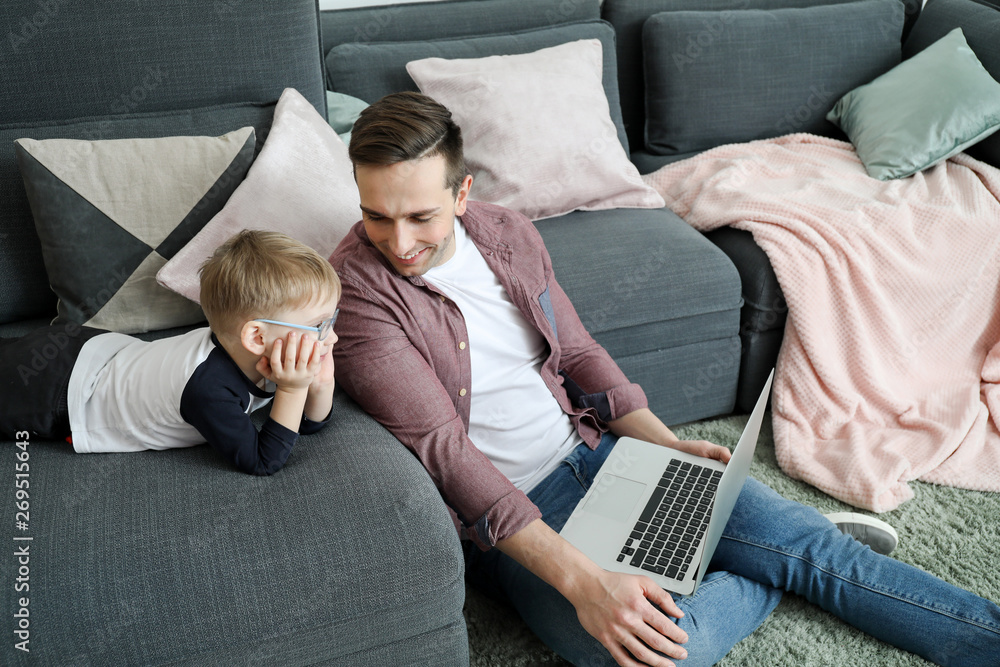 Young father with little son watching cartoons at home