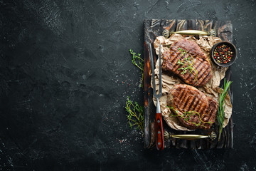 Grilled beef steak medium rare on a black stone table. Top view. Free space for your text.