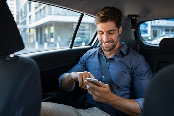 Wall Mural - Happy business man in car using phone