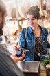 © jackfrog - A  young woman makes a contactless card payment in a store