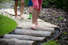 Detail Of Kids Legs Walking On Wooden Pathway Barefoot