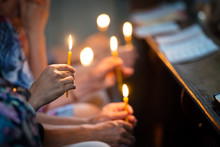 Religious People Holding Lit Candles In Church