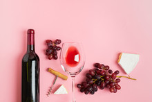A Bottle Of Wine An Empty Glass A Bunch Of Grapes Slices Of Cheese On A Gentle Pink Background. Minimalism. Top View