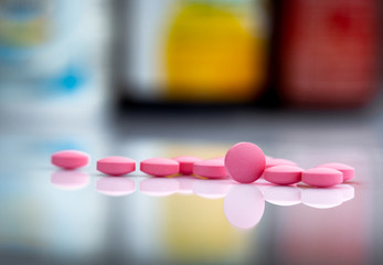 Wall Mural - Pink tablets pills on blurred background of drug bottle in drugstore or pharmacy department in hospital. Pharmaceutical industry. Pharmaceutics concept. Medicine for treatment illness. Healthcare.