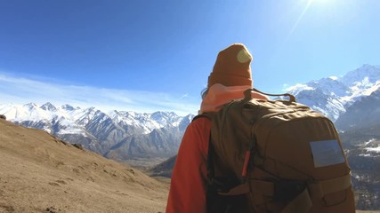 Wall Mural - Portrait of a happy girl traveler photographer in a hat and sunglasses with a camera around his neck and a phone in his hands on the background of mountains takes pictures on his smartphone