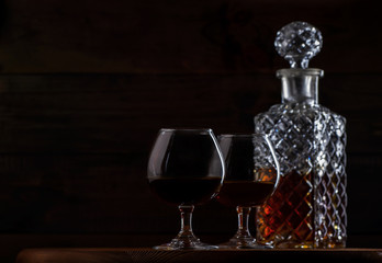 Brandy or cognac in glasses and a decanter on a brown wooden background